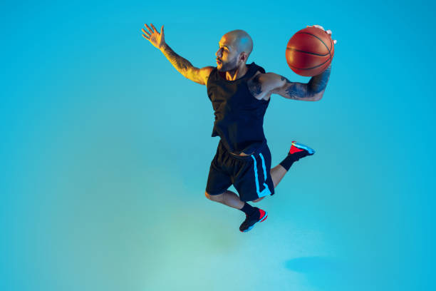 istock Young basketball player training isolated on blue studio background in neon light 1209055161