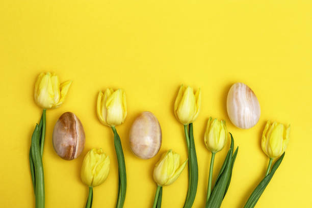 istock Bright blooming flowers and decorative easter eggs from gemstone onyx. Pattern from yellow tulips and stone eggs and with copy space. Holiday spring concept. 1209055189