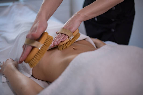 Young woman is getting bamboo brush massage at spa stock photo