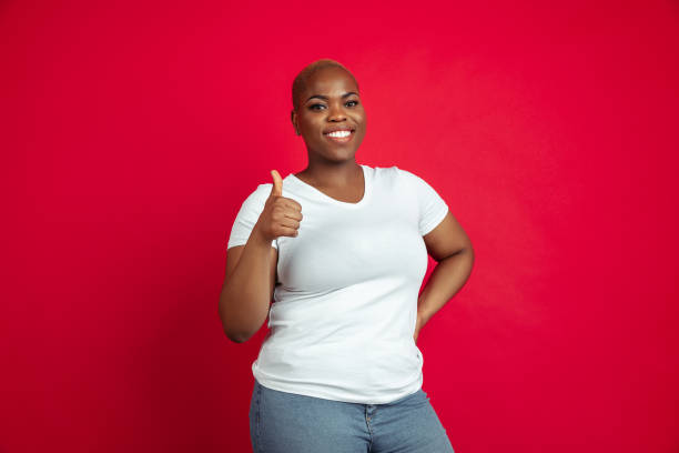 istock African-american young woman's portrait on red background 1209058292