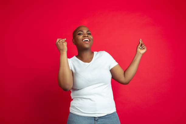 istock African-american young woman's portrait on red background 1209058376