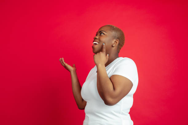 istock African-american young woman's portrait on red background 1209058460