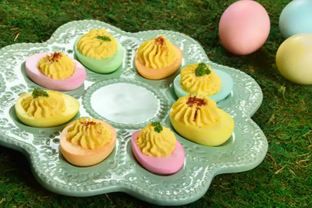 A holiday twist on the classic deviled egg, with the egg whites dyed in festive colors, perfect for an Easter brunch.