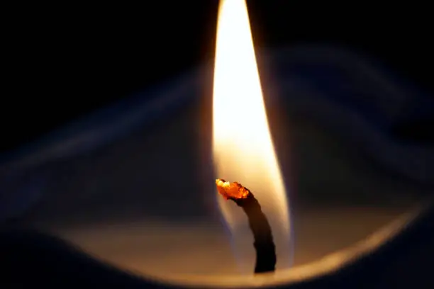 The closeup-macro photography of a burning candle light isolated on the black background