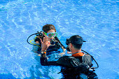 beautiful young woman taking a scuba diving lesson in the picine