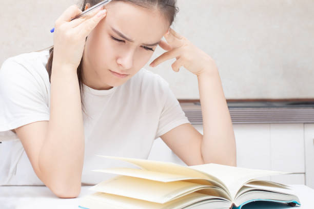 istock A girl sits at a table and thinks next to a book. 1209063472