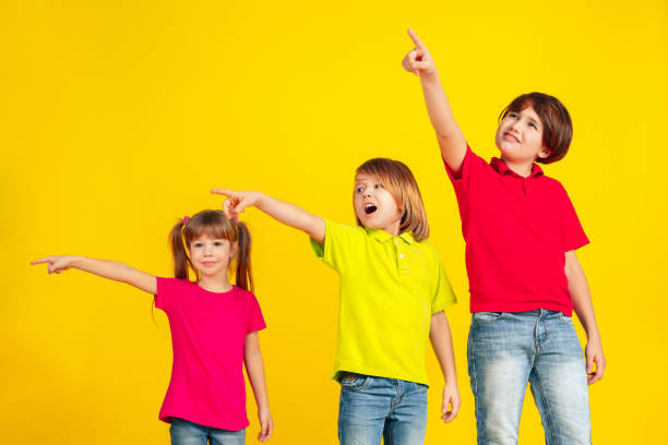 istock Happy children playing and having fun together on yellow studio background 1209064391