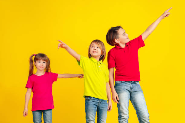 istock Happy children playing and having fun together on yellow studio background 1209064409