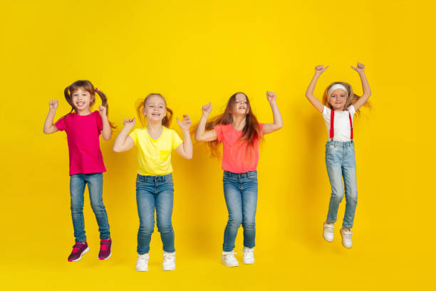 istock Happy children playing and having fun together on yellow studio background 1209064470
