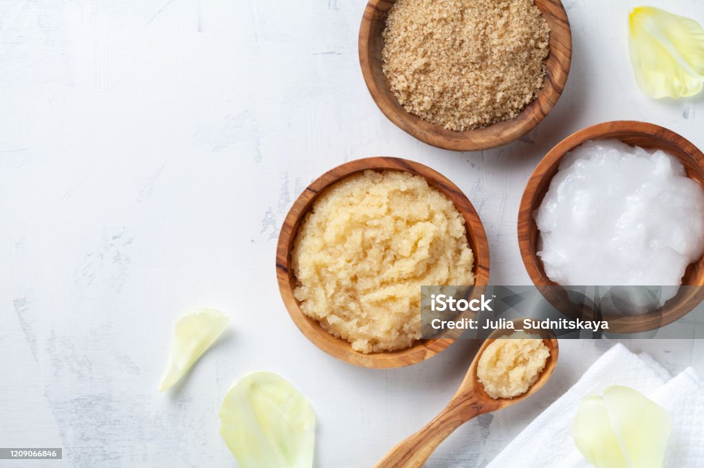 Sugar body scrub with ingredients on white stone table. Homemade cosmetic for spa and beauty. Sugar body scrub with ingredients on white stone table. Homemade cosmetic for spa and beauty with copy space. Exfoliation Stock Photo