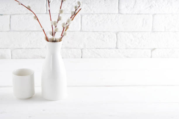 istock Easter concept White vase with willow branch and cups on a white table Copy space 1209075065