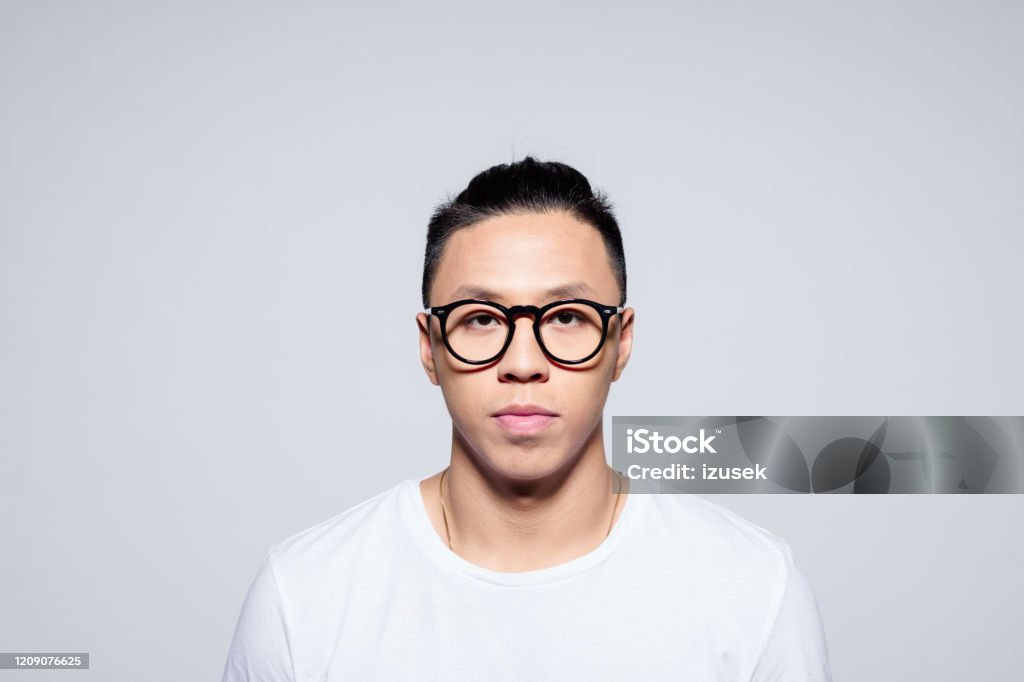 Handsome asian young man wearing glasses Headshot of serious asian young man wearing white t-shirt and glasses, looking at camera. Portrait on white background. Portrait Stock Photo