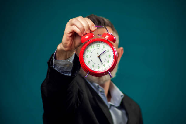 istock Bearded businessman holding alarm clock. Time management concept 1209076688