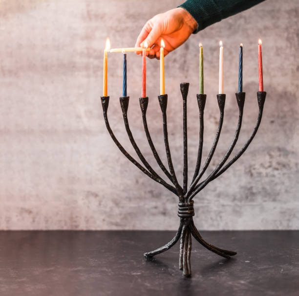ハヌカのためのメノーラにろうそくを点灯する手のトリミングされた画像。 - menorah hanukkah candle human hand ストックフォトと画像