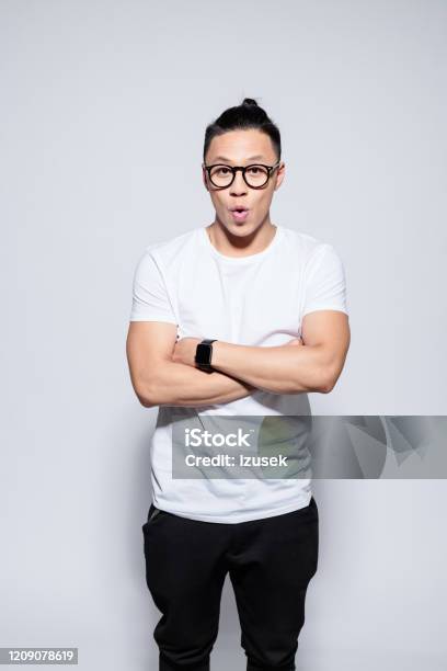 Surprised Asian Young Man Standing With Arms Crossed Stock Photo - Download Image Now