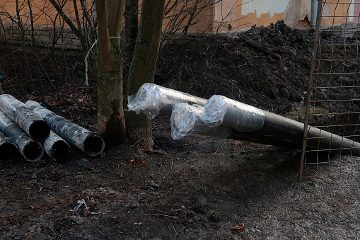 black plastic pipes wrapped in polyethylene sticking out of the ground