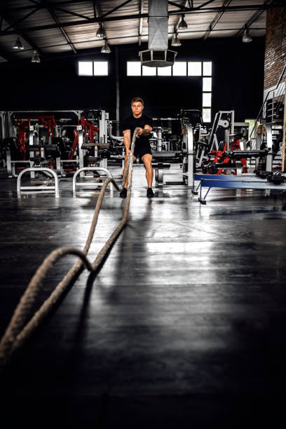 istock Fit young man training with battle ropes in a gym 1209083880