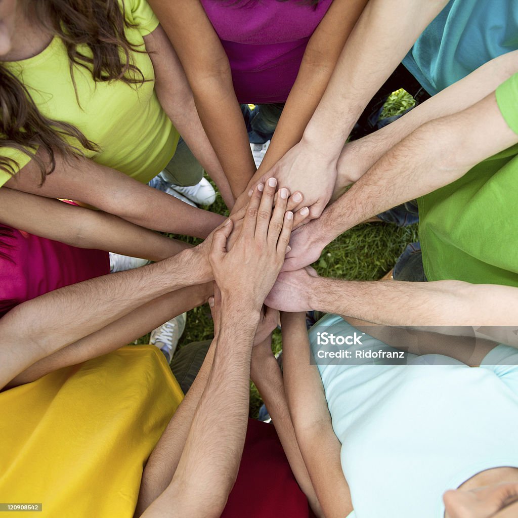High view of numerous people joining hands High view of team of friends showing unity with their hands together. Sea Of Hands Stock Photo