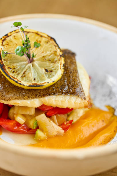 istock Closeup Roasted pike perch or cod fish with baked vegetables. Dish decorated with a slice of lemon. Restaurant menu 1209085547