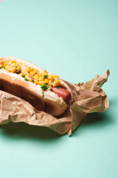 istock yummy hot dog with corn in paper on blue 1209086316