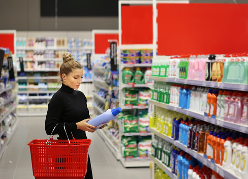 Mujer comprando en supermercado leyendo información de productos. (shampoo, jabón, gel de ducha,) photo