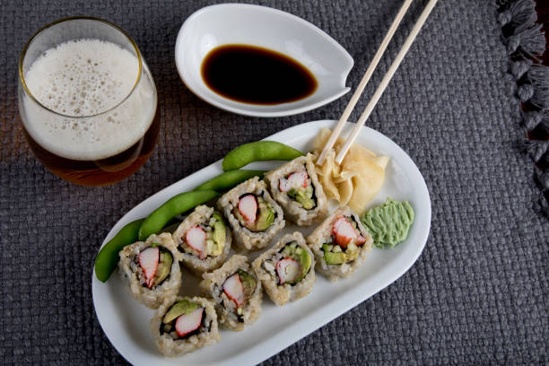 california roll sushi en un plato con salsa de soja en el costado y una cerveza para beber - maki sushi japanese culture food and drink still life fotografías e imágenes de stock