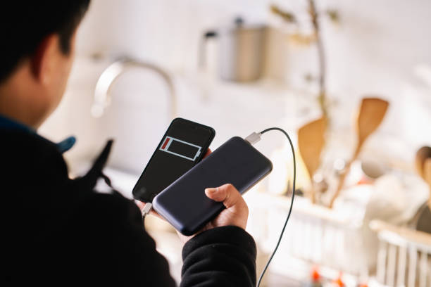 istock Male is holding in hand black smartphone with black usb and blue power bank. 1209088564