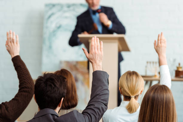 back view of buyers raising hands to auctioneer during auction back view of buyers raising hands to auctioneer during auction auction photos stock pictures, royalty-free photos & images