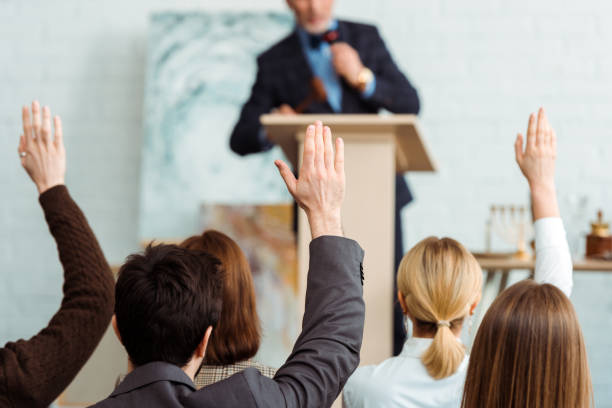 back view of buyers raising hands to auctioneer during auction - bidder imagens e fotografias de stock