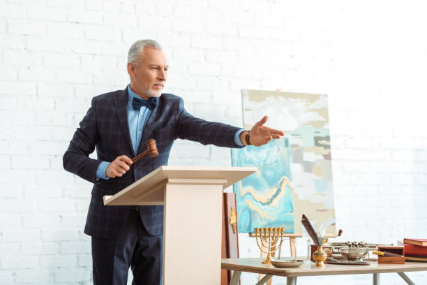 handsome auctioneer holding wooden gavel and pointing with hand during auction handsome auctioneer holding wooden gavel and pointing with hand during auction auction photos stock pictures, royalty-free photos & images