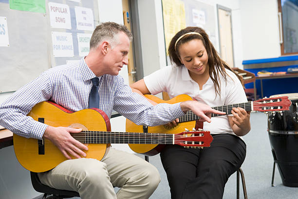 школьница и учитель играют гитара в музыкальный класс - guitar lessons стоковые фото и изображения