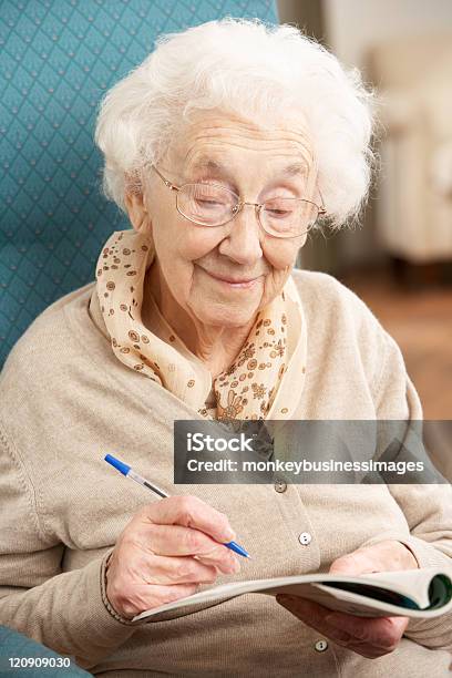 Mujer Senior Relajante En Casa De Finalizar Crossword Foto de stock y más banco de imágenes de Mujeres mayores