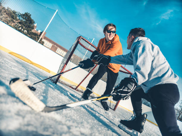 vater und sohn spielen hockey im freien - ice skating ice hockey child family stock-fotos und bilder