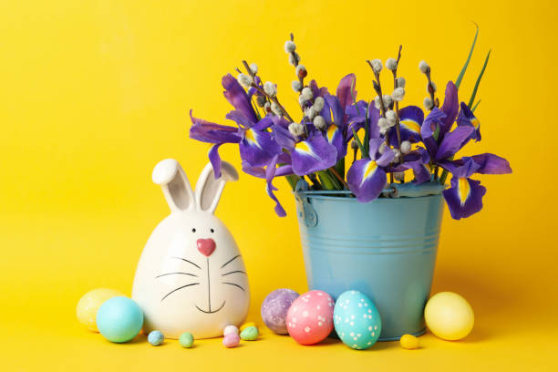 istock Bunny, Easter eggs and bucket with flowers on yellow background 1209095202