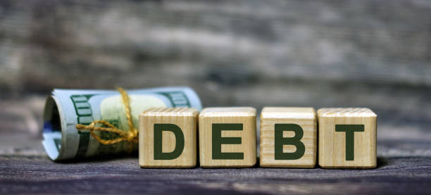 istock DEBT word concept on cubes with a banknote 1209095328