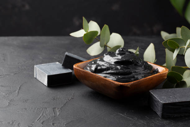 Spa and bath concept. Dead sea mud, coal black soap, eucalyptus on black background. Copy space.
