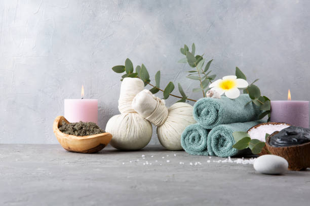 istock Beautiful spa relax concept. Coffee with cinnamon scrub, green tea scrub, cotton pouches with herbs for massage, sea stones and other Spa accessories on table. Copy space. 1209097567