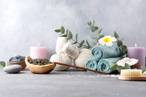 Beautiful spa relax concept. Coffee with cinnamon scrub, green tea scrub, cotton pouches with herbs for massage, sea stones and other Spa accessories on table. Copy space.