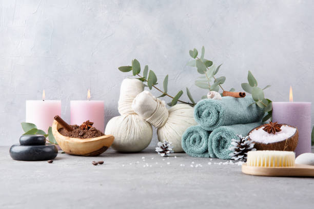 istock Beautiful spa relax concept. Coffee with cinnamon scrub, green tea scrub, cotton pouches with herbs for massage, sea stones and other Spa accessories on table. Copy space. 1209097589