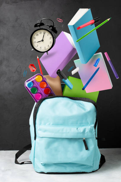 istock Back to school 1 September. Backpack and flying books, notebooks, pencils and alarm clock isolated on black board background 1209098728
