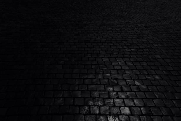 istock Black background. Old cobblestone pavement in perspective. Abstract background. Black and white photo. 1209103376