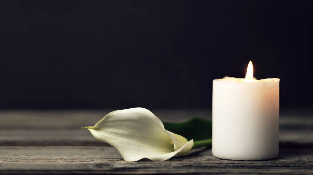 Burning candle and white calla on dark background with copy space. Sympathy card Burning candle and white calla on dark background with copy space. Sympathy card candlelight photos stock pictures, royalty-free photos & images