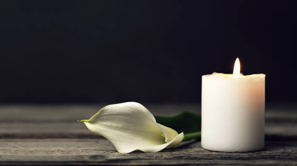 Burning candle and white calla on dark background with copy space. Sympathy card Burning candle and white calla on dark background with copy space. Sympathy card calla lily stock pictures, royalty-free photos & images