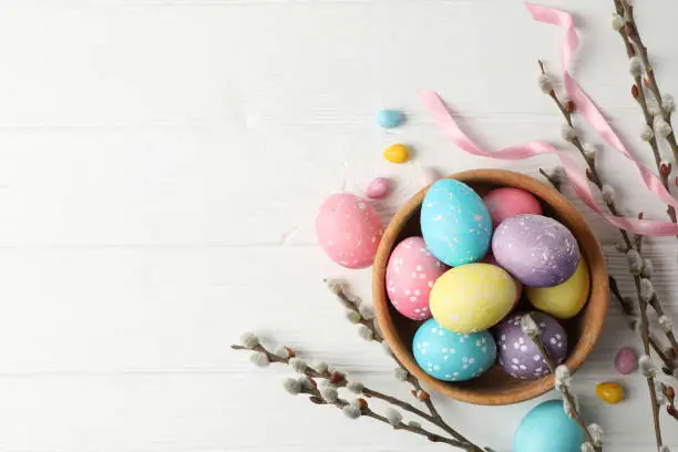 Photo of Composition with Easter eggs on white wooden background, space for text