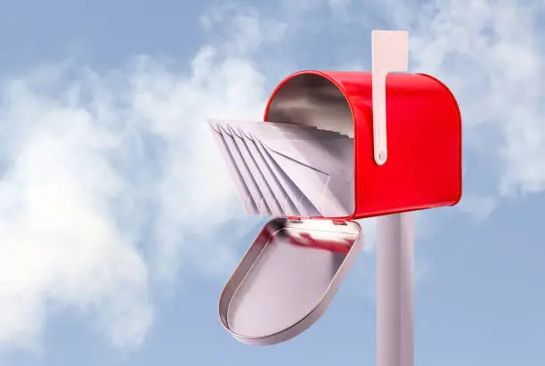 Red open mailbox with five white envelopes and sky background