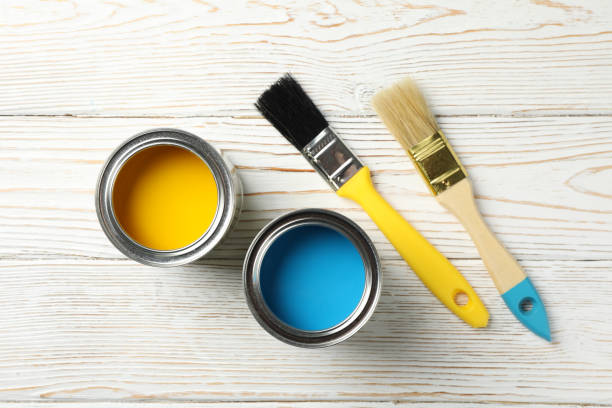 istock Paint cans and brushes on wooden background, top view 1209105402