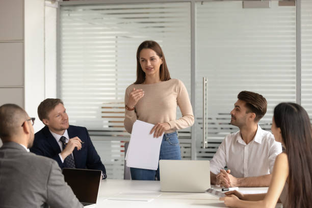 istock Confident female speaker standing, explaining project results to multiracial colleagues. 1209105754