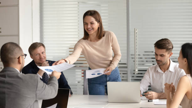 istock Smiling female presenter handing out documents with charts. 1209105762