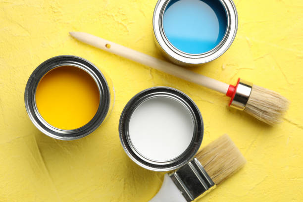 istock Paint cans and brushes on yellow background, top view 1209105951