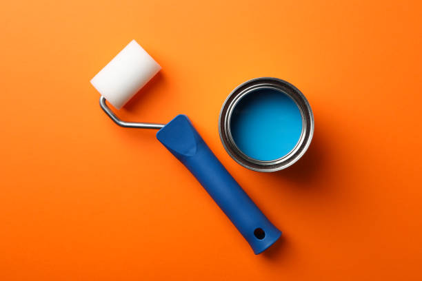 istock Can of blue paint and roller on orange background, top view 1209105999